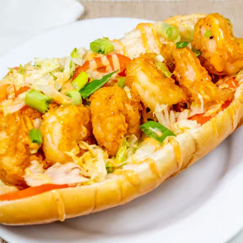 Urban Grill's shrimp po'boy with crispy fried shrimp, lettuce, tomato, and sauce on a bun.